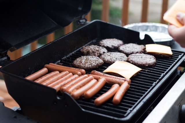 burgers and hot dogs cooking on a barbecue