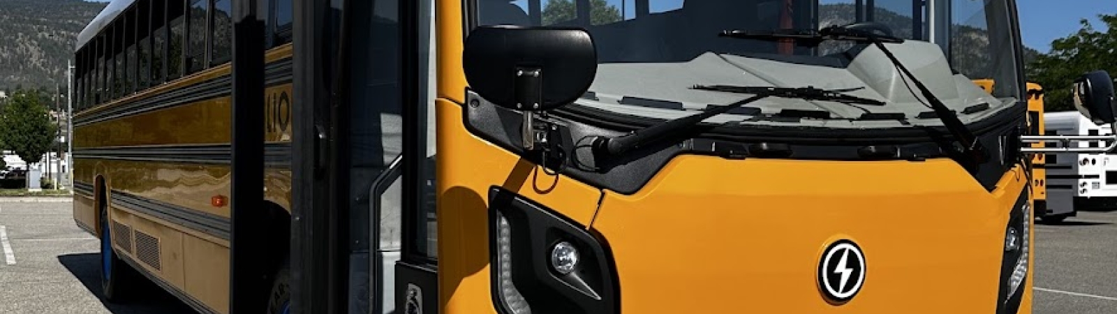 An electric school bus in a parking lot under a clear blue sky