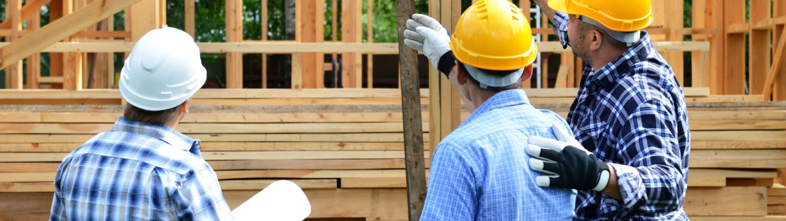 construction workers on a job site with a partially constructed house in the background