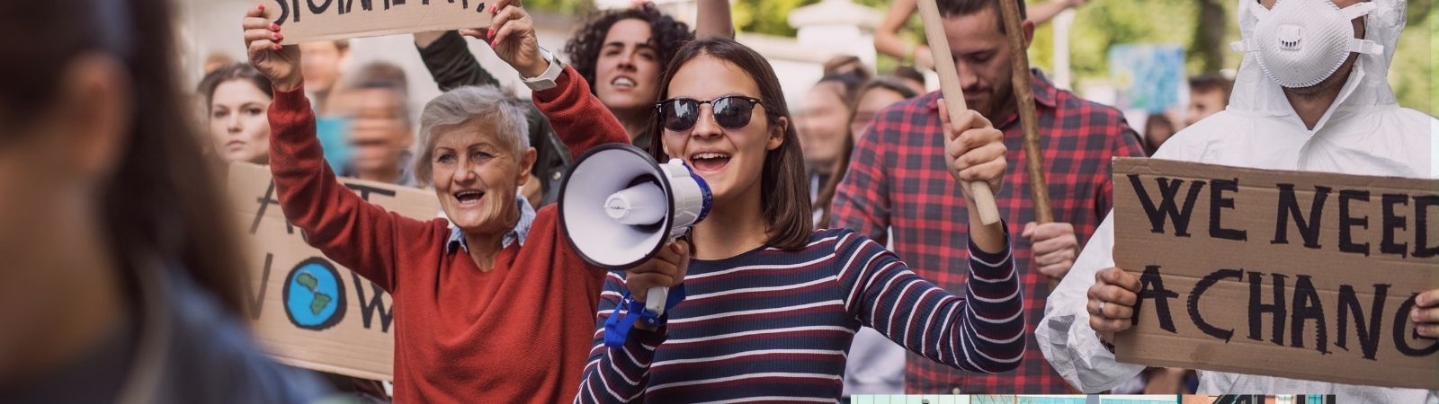 woman with a megaphone at a rally next to someone with a sign that says "We Need a Change"