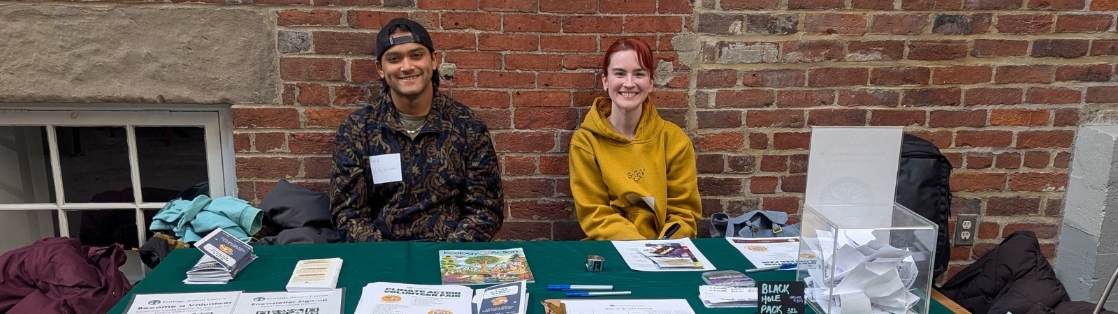 Two young people sitting at an EAC volunteer table, smiling