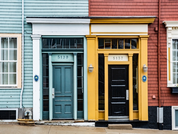 The front doors of a split house one side blue and one side red with yellow trim.
