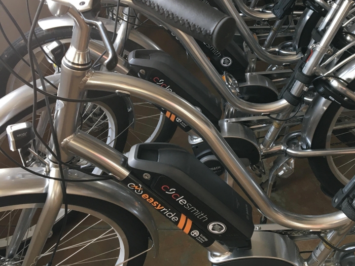 close up of silver ebikes in a row with black seats.