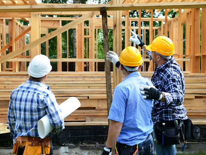 construction workers on a job site with a partially constructed house in the background