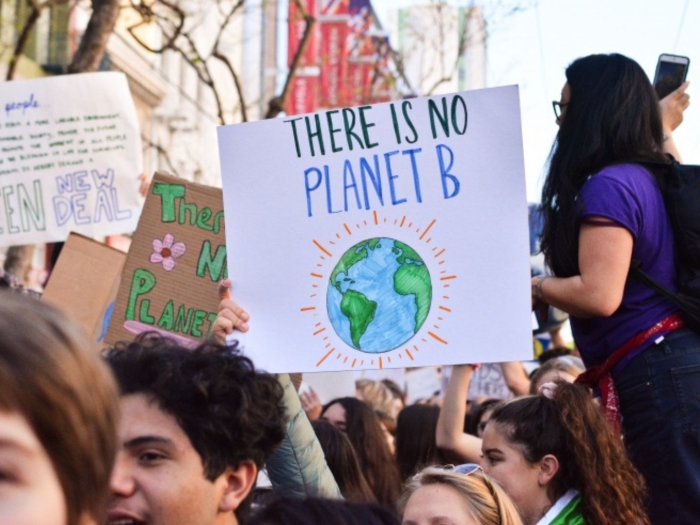 Students at a climate strike in halifax. a sign in the foreground reads "there is no planet B" with a picture of a globe