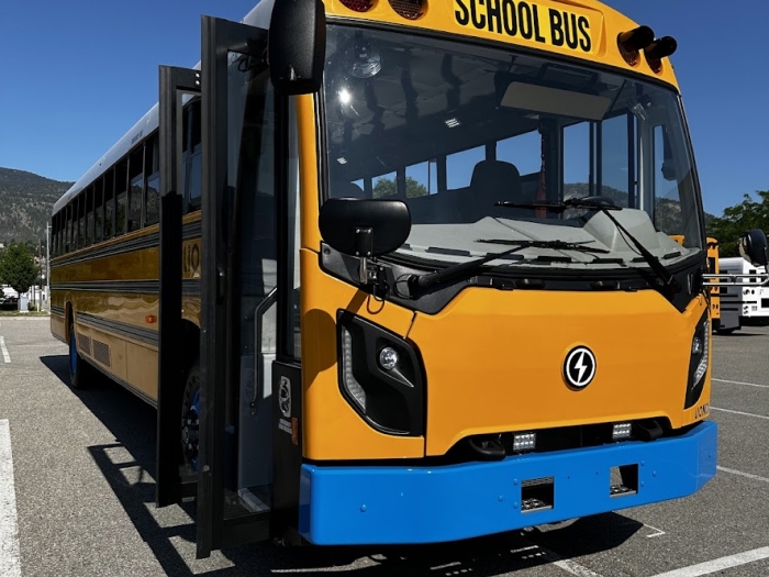 An electric school bus in a parking lot under a clear blue sky