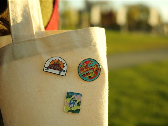 three badges pinned to a tote bag