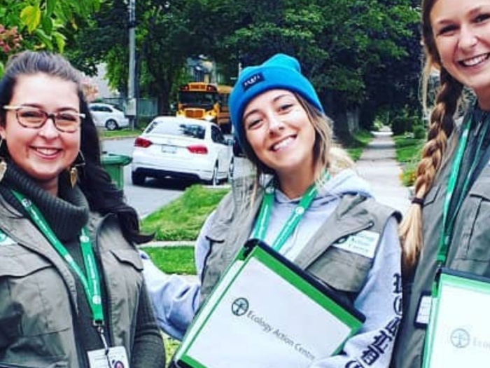 Three young canvassers smiling and holding clipboards